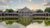 A large brick building is reflected in a pond.